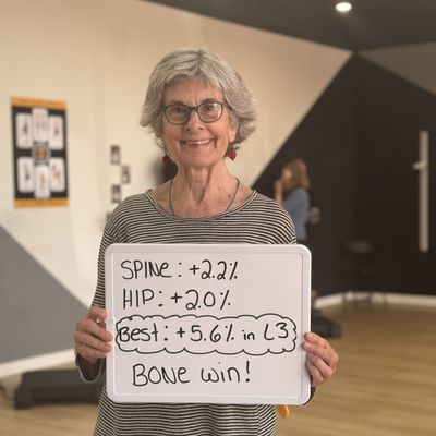 OsteoStrong member Diane holding her whiteboard with DEXA numbers